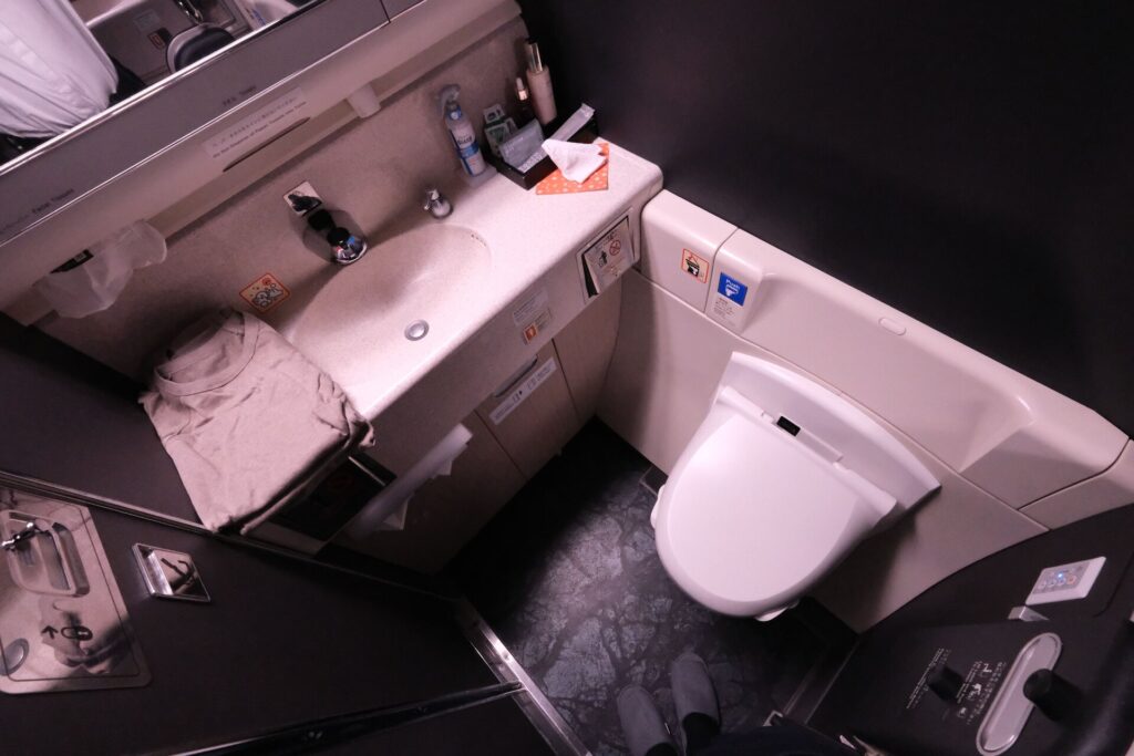 JAL first class restroom with folded PJs and amenities on the basin side.