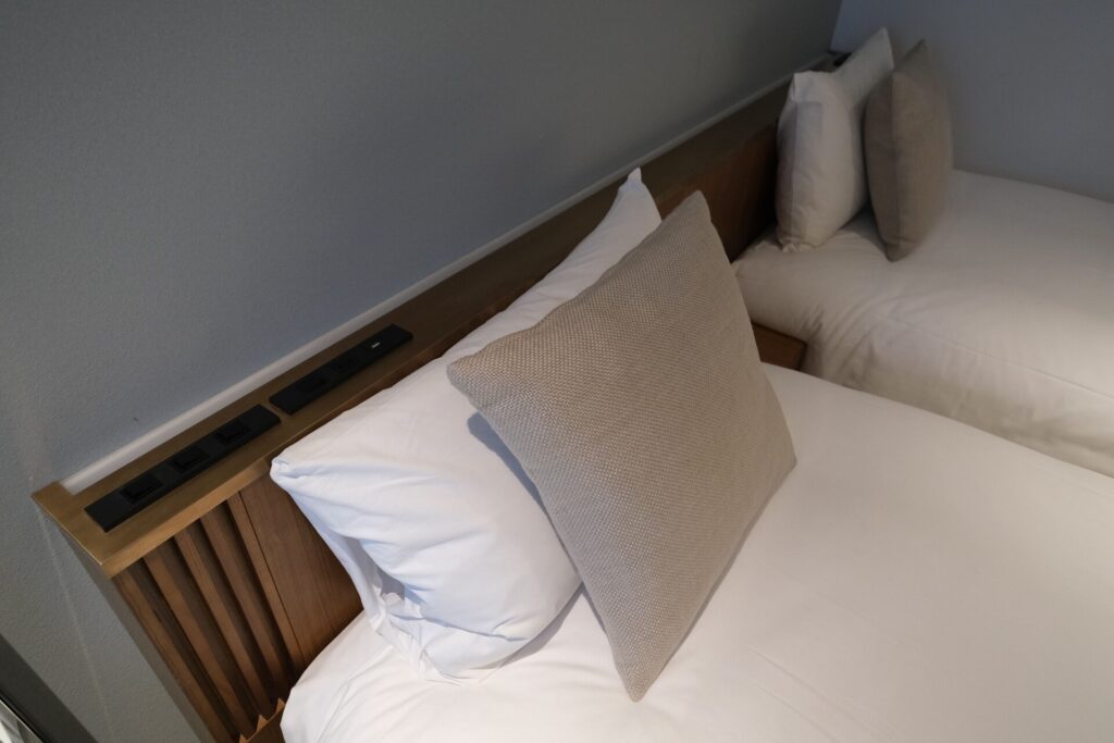 Two pillows for each bed are provided, a standard size and a throw pillow. There is also a light, power and controls behind the bed.
