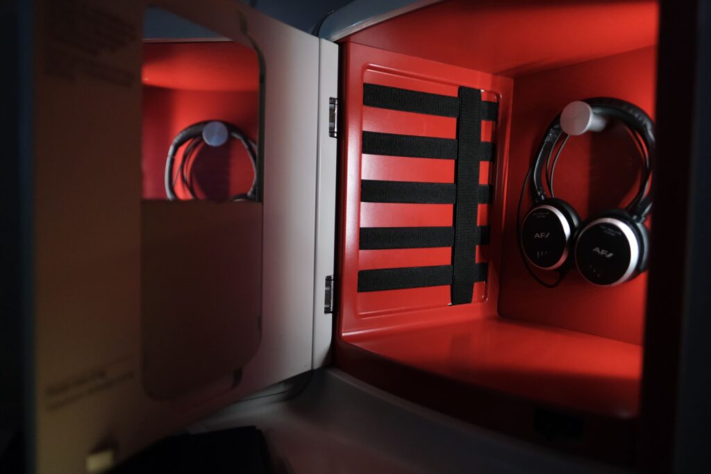 Air France Business Class headphones are found inside this large side panel storage, which also comes with a small mirror.