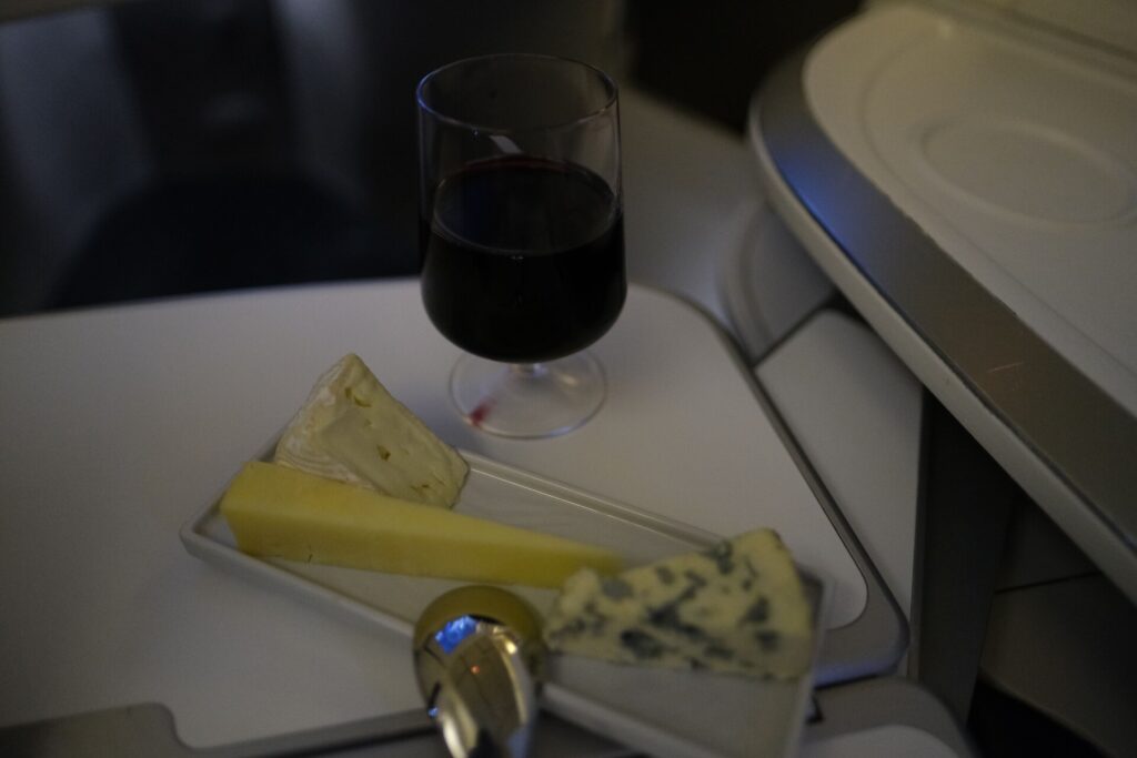 Red wine and a Cheese plate, with a variety of tasty cheeses. 
