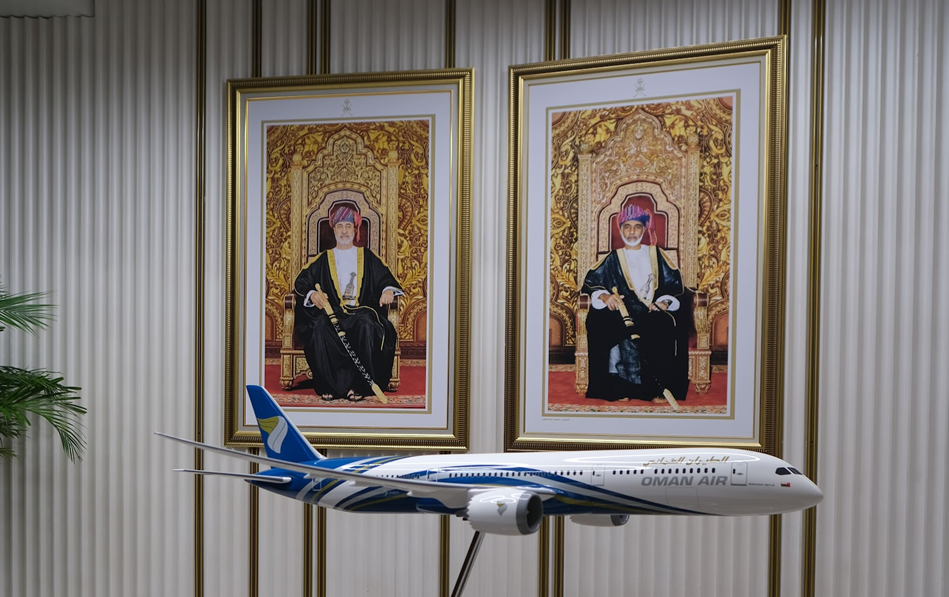 An Oman Air Plane scale model and a framed image of the Sultans of Oman in the entry lobby..