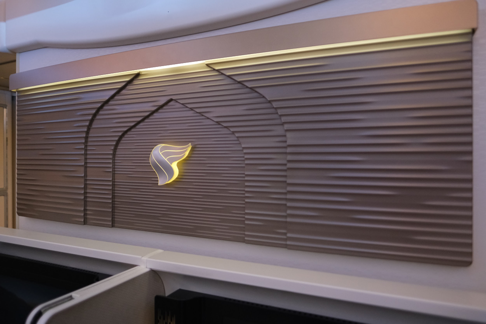 The elegant Oman Air logo, lighted, at the front of the First Class cabin.