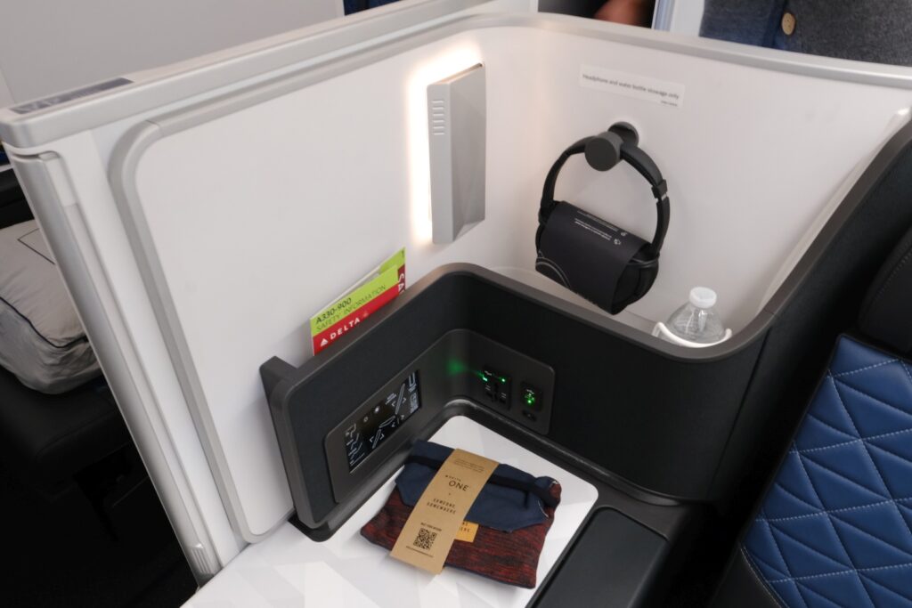 Side table with amenity kit, headphones, and power outlets and seat controls