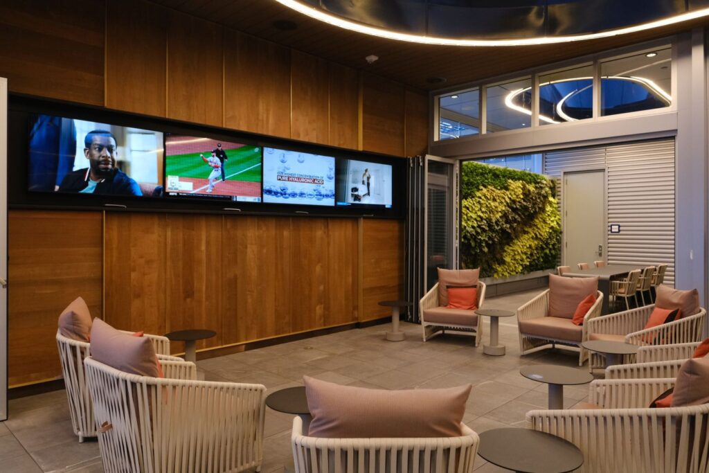 TV wall with seating, and "Plant Wall" meeting table in the back