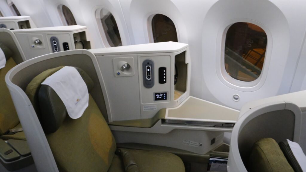 View of the seat controls, tray table and head phones tucked away on the right
