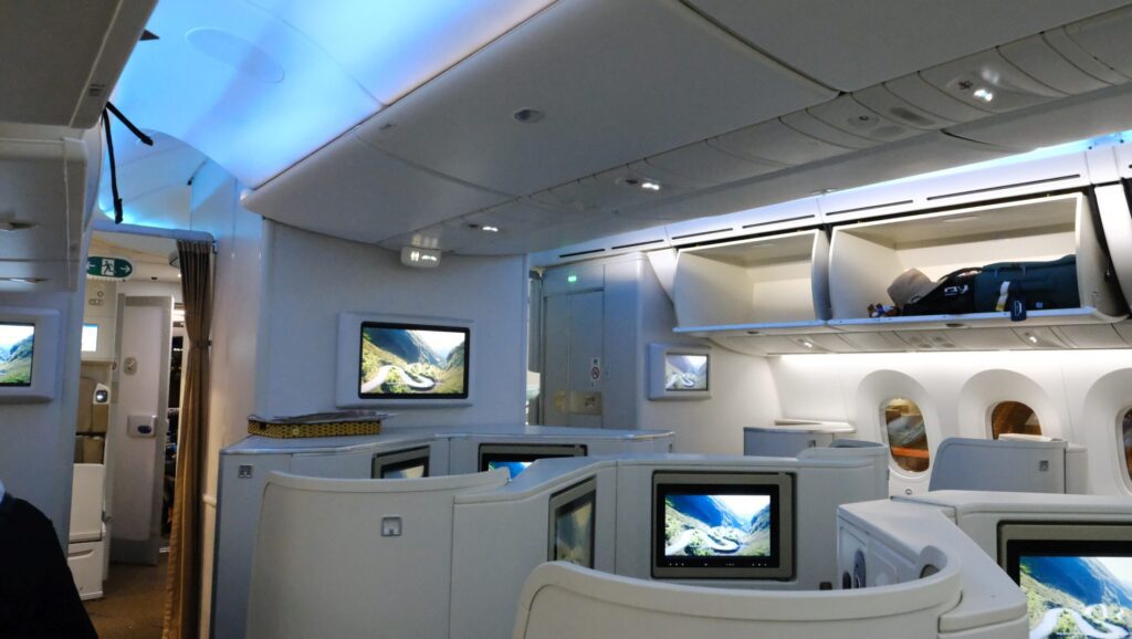 Sky blue interior lighting and TVs at the front of the business class cabin